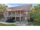View of a brick home's rear exterior, featuring a covered patio, a walkout basement, and manicured landscaping at 5250 Sartin Rd, Burlington, NC 27217