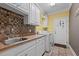 Functional laundry room with tiled floors, ample cabinet space, a utility sink, and modern washer and dryer units at 5250 Sartin Rd, Burlington, NC 27217