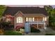 Spacious rear exterior of a brick house showcasing a raised porch, a covered patio, and beautiful landscaping at 5250 Sartin Rd, Burlington, NC 27217