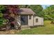 Charming outdoor shed with a dark door, a window, surrounded by greenery and fresh landscaping at 5250 Sartin Rd, Burlington, NC 27217