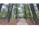 A long winding gravel driveway leads to a home surrounded by lush trees and greenery at 5728 Carriagehouse Ct, Apex, NC 27539