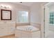 Bathroom featuring a jacuzzi tub with window, vanity with mirror, and neutral tile at 7000 Millstone Ridge Ct, Raleigh, NC 27614