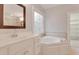 Luxurious bathroom with vanity sink and jacuzzi tub. Decorative window adds charm at 7000 Millstone Ridge Ct, Raleigh, NC 27614