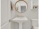 Bathroom featuring a pedestal sink, round mirror, and toilet at 7000 Millstone Ridge Ct, Raleigh, NC 27614