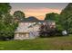 View of a cream colored house, including deck and walk-out basement, during sunset at 7000 Millstone Ridge Ct, Raleigh, NC 27614