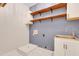 Laundry room with blue accent wall, open shelving, and stainless steel utility sink at 7000 Millstone Ridge Ct, Raleigh, NC 27614