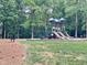 Community playground with slides, swings, and a bench in a wooded area at 7000 Millstone Ridge Ct, Raleigh, NC 27614