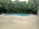 A swimming pool sits in a paved area, surrounded by a forest and some lounge chairs at 7000 Millstone Ridge Ct, Raleigh, NC 27614