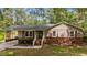 Charming single-story home with tan siding, brick foundation, and red shutters surrounded by mature trees at 702 Wedgewood Ave, Zebulon, NC 27597