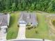 Aerial view of a gray-shingled house showcasing landscaping, a driveway, and green spaces on a sunny day at 704 Long Lake Dr, Fuquay Varina, NC 27526