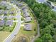 Aerial view of a new neighborhood with manicured lawns and landscaping, featuring homes around a pond and wooded area at 704 Long Lake Dr, Fuquay Varina, NC 27526