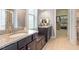 Bathroom featuring granite countertop, dual sinks, dark wood cabinetry, and a walk-in closet for ample storage at 704 Long Lake Dr, Fuquay Varina, NC 27526