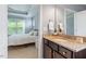 Bathroom vanity with granite countertop and view to the main bedroom with white bedding at 704 Long Lake Dr, Fuquay Varina, NC 27526