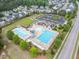 Aerial view of a neighborhood pool with lounge chairs, a playground, parking, and manicured green spaces at 704 Long Lake Dr, Fuquay Varina, NC 27526