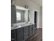 Bathroom featuring a dual sink vanity with gray cabinets, a large mirror, and luxury vinyl plank flooring at 712 Emmer St, Rolesville, NC 27571