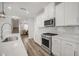 Bright kitchen features stainless steel appliances, white cabinetry, light gray backsplash and quartz countertops at 712 Emmer St, Rolesville, NC 27571