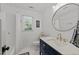 All white bathroom with navy vanity, modern fixtures, and decorative mirror at 7204 Laketree Dr, Raleigh, NC 27615