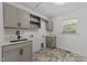 Well-lit laundry room features gray cabinets, modern fixtures, and stylish tile flooring at 7204 Laketree Dr, Raleigh, NC 27615