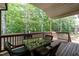 Covered deck with a glass table and wicker chairs overlooks serene woods at 7660 Channery Way, Raleigh, NC 27616