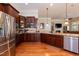Open kitchen featuring stainless steel appliances, hardwood floors, granite counters, and dark wood cabinets at 7660 Channery Way, Raleigh, NC 27616