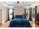 Bright main bedroom featuring hardwood floors, a tray ceiling, and large windows with curtains at 7660 Channery Way, Raleigh, NC 27616