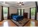 Main bedroom offering a tray ceiling, hardwood floors, ceiling fan, and many windows with curtains at 7660 Channery Way, Raleigh, NC 27616