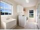 Well-lit laundry room featuring a utility sink, washer, dryer, storage cabinets, and a window at 78 Cross Creek Ct, Timberlake, NC 27583