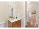 Stylish half-bathroom with wood vanity, granite counters, and a view into the hall with kitchen at 844 Cozy Oak Ave, Cary, NC 27519