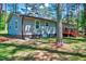 Backyard view of home with a wooden deck, well-maintained lawn, and surrounded by lush trees at 9220 Old Cascade Dr, Garner, NC 27529