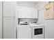 Modern laundry room with front loading washer and dryer, with white cabinets for storage, and decorative artwork at 94 Two Creeks, Chapel Hill, NC 27517