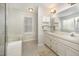 Bright bathroom with a large mirror, double sinks, and a separate tub area at 9408 Bells Valley Dr, Raleigh, NC 27617