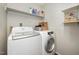 Functional laundry room equipped with modern washer and dryer units and shelving for storage at 9408 Bells Valley Dr, Raleigh, NC 27617