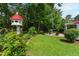 Lush backyard featuring a birdhouse, stone patio with seating, and mature trees at 9517 Candor Oaks Dr, Raleigh, NC 27615