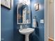 Charming powder room featuring a pedestal sink, ornate mirror, and stylish blue walls at 9517 Candor Oaks Dr, Raleigh, NC 27615