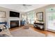 Bright living room with fireplace, hardwood floors, and large windows at 9517 Candor Oaks Dr, Raleigh, NC 27615
