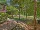 Lush backyard featuring stone steps, a tranquil waterfront, and mature trees, creating a serene setting at 105 Highlands Lake Dr, Cary, NC 27518
