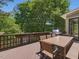 Outdoor wooden deck with dining table set and built-in grill overlooking the lush green landscape at 105 Highlands Lake Dr, Cary, NC 27518