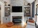 Elegant living room with stone fireplace, built-in shelving and flat screen television at 105 Highlands Lake Dr, Cary, NC 27518