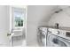 Laundry room featuring a window, utility sink, tile flooring, overhead wire rack, and front loading washer and dryer at 108 Nimbus Ct, Cary, NC 27513