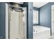 Bathroom with shower and tub, dark blue walls, and white trimming on the door at 109 Lyngrove St, Holly Springs, NC 27540