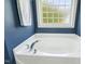 Bathroom with a garden tub with chrome fixtures and a frosted window for privacy at 109 Lyngrove St, Holly Springs, NC 27540