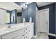 Bathroom with blue walls, double sink, marble counter tops, updated lighting, and walk-in shower at 109 Lyngrove St, Holly Springs, NC 27540