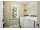 Bright laundry room featuring a window, updated machines, and storage shelves for convenience at 109 Lyngrove St, Holly Springs, NC 27540