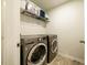 This functional laundry room showcases modern washer and dryer units, with shelving providing ample storage space at 1101 Compass Dr, Durham, NC 27713