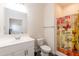 Bright bathroom featuring a clean white vanity, toilet, and shower with vibrant, patterned curtains at 116 Laurel Ave, Durham, NC 27701