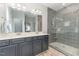 Stylish bathroom featuring dual vanity, gray tile shower, and glass enclosure at 1302 Reading Ct, Burlington, NC 27217
