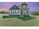 Charming two-story home with a welcoming front porch and well-manicured lawn and stylish landscaping at dusk at 1302 Reading Ct, Burlington, NC 27217