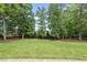 Lush backyard with mature trees and a view of the house at 1308 Mackinaw Dr, Wake Forest, NC 27587