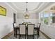 Bright dining room featuring decorative wainscoting, a black dining table, and tray ceiling at 1308 Mackinaw Dr, Wake Forest, NC 27587