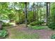 Lush backyard with mature trees, stone pathway, and a charming wooden bridge at 1416 Dunbar Ct, Cary, NC 27511